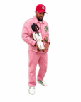 Person wearing a pink outfit with a graphic design, white sneakers, and a red cap on a white background